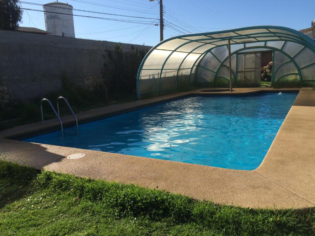 a swimming pool with a greenhouse in a yard at Cabañas Costatour Quintero in Quintero