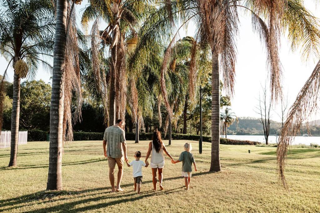 a family walking through a park with palm trees at Wisemans Retreat in Wisemans Ferry
