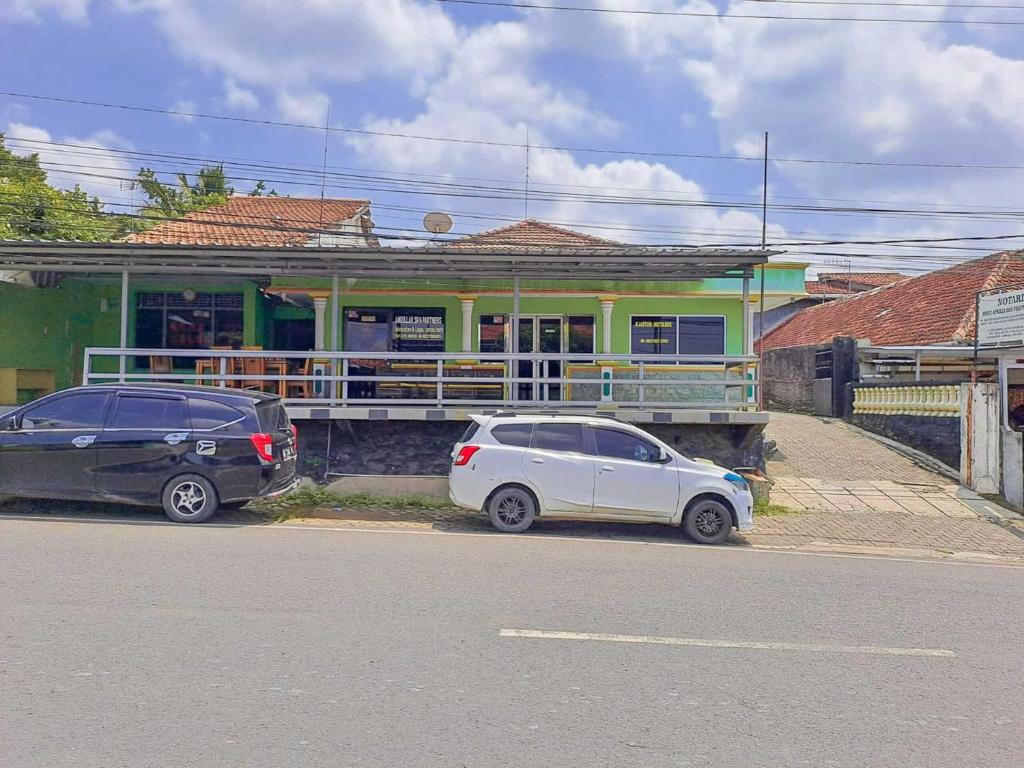 deux voitures garées devant un bâtiment dans l'établissement SPOT ON 93840 Guest House Amanda Syariah, à Bandar Lampung