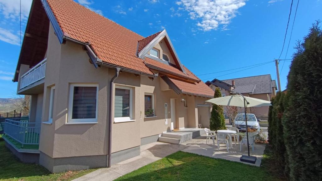 a house with an umbrella and a table and chairs at Guest House Green Field in Sarajevo