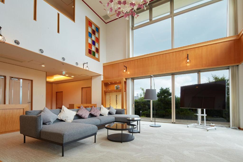 a living room with couches and a flat screen tv at Rembrandt Atsugi BETTEI in Atsugi