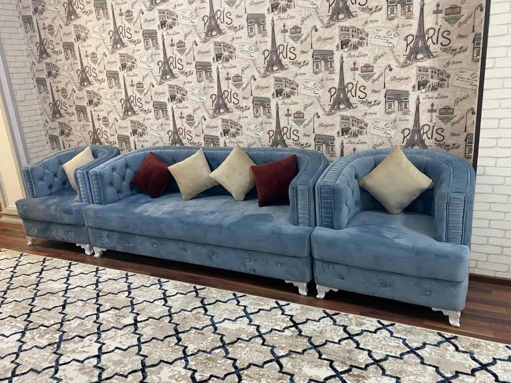um sofá azul com almofadas numa sala de estar em Квартира 3-ух Комнатная в центре города em Fergana