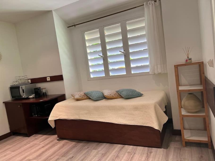 a bedroom with a bed with pillows and a window at Bungalow Sarraméa in Sarraméa
