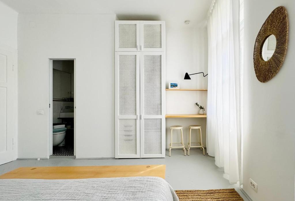 a bedroom with white walls and a bed and a mirror at Jardin Rooms in Split