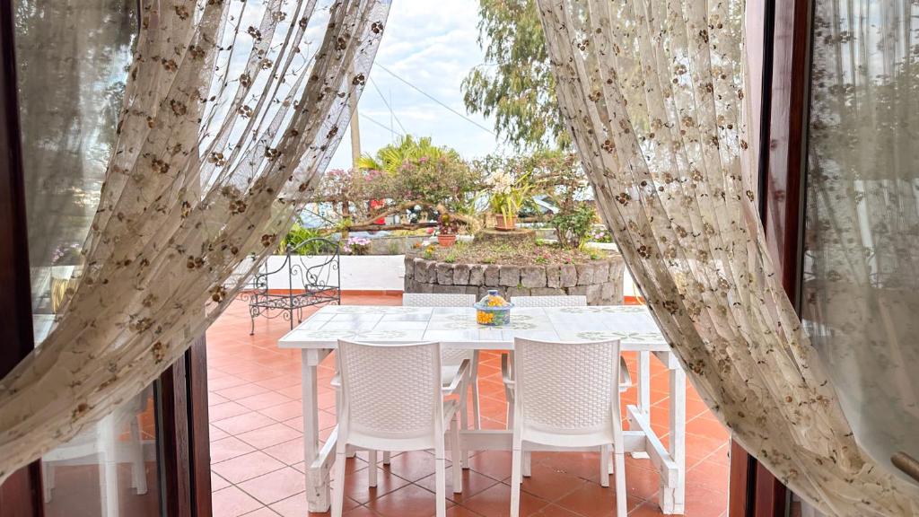 einen weißen Tisch und Stühle in einem Zimmer mit Fenster in der Unterkunft Villa La Magnolia in Ischia
