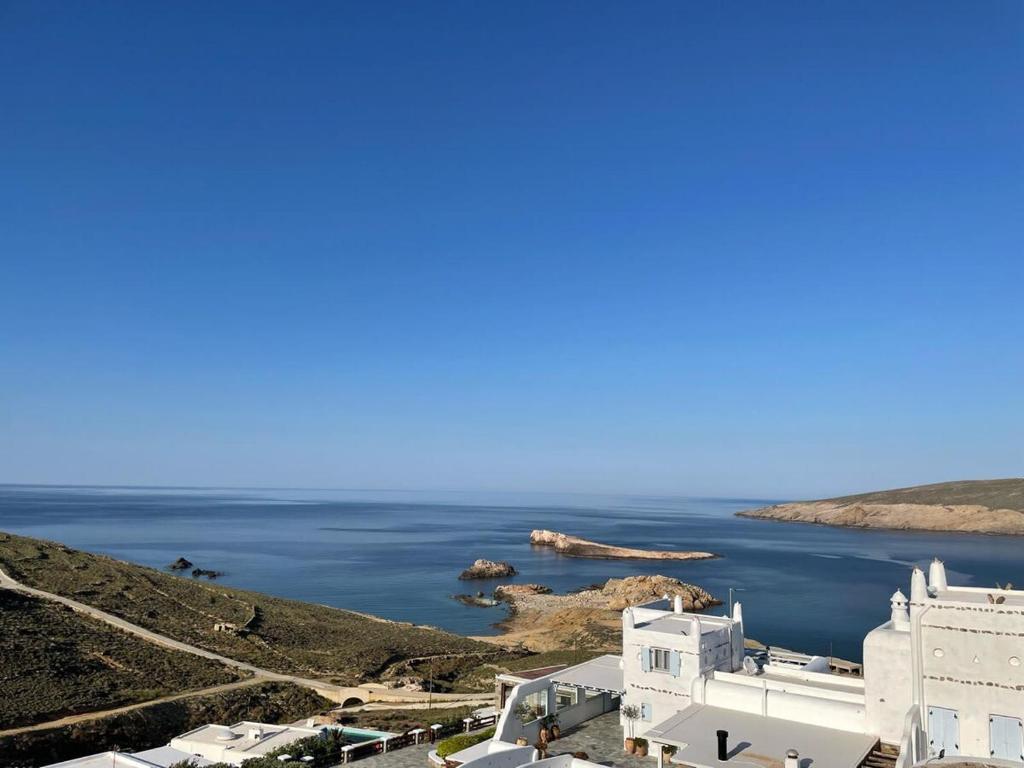 vista sull'oceano e su un edificio bianco di Mykonian 4 Bd Ocean Dream House in Agios Sostis ad Agios Sostis Mykonos