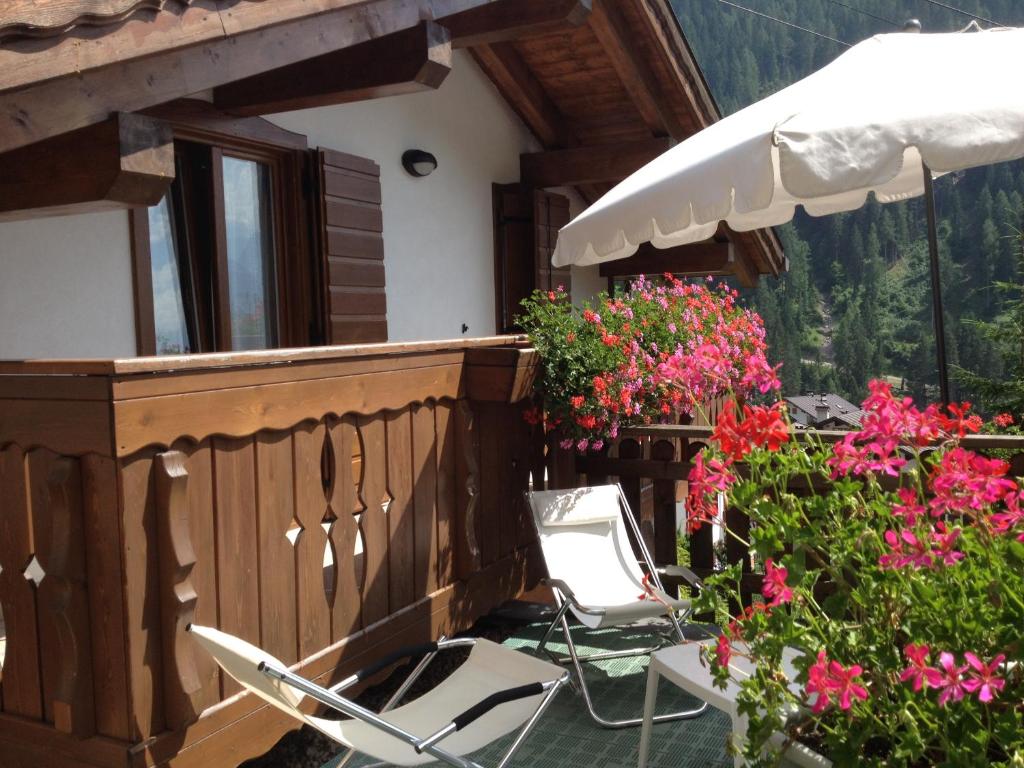 un paio di sedie e un ombrellone su un balcone fiorito di Casa Vacanze Villa Elena ad Alleghe