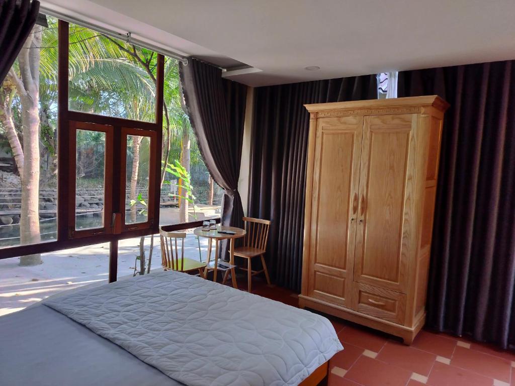 a bedroom with a bed and a large window at Khu du lịch Suối Ong in Buôn Erang