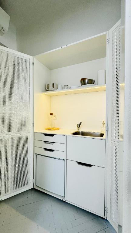 a kitchen with white cabinets and a sink at Jardin Rooms in Split