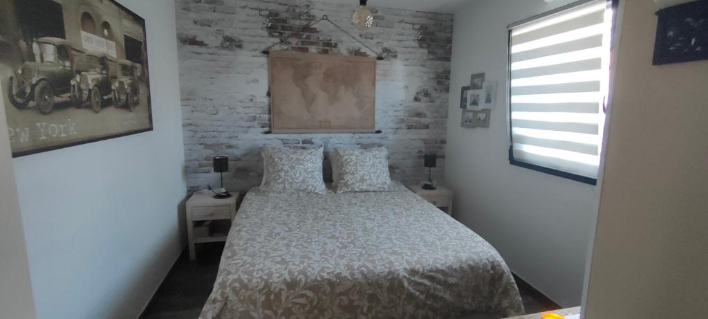 1 dormitorio con cama y pared de ladrillo en chambre d'hôte La Paisible, en Treize-Vents