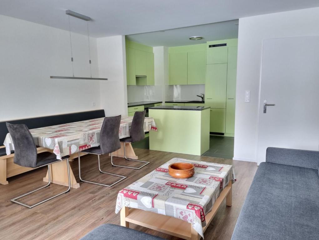 een woonkamer met een tafel en stoelen en een keuken bij Holiday flat for skiing couples Triangel D - Parpan Lenzerheide in Parpan