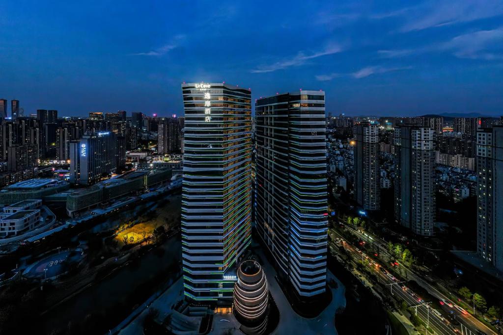 uitzicht op twee hoge gebouwen in een stad 's nachts bij UrCove by HYATT Hangzhou Riverside CBD in Hangzhou