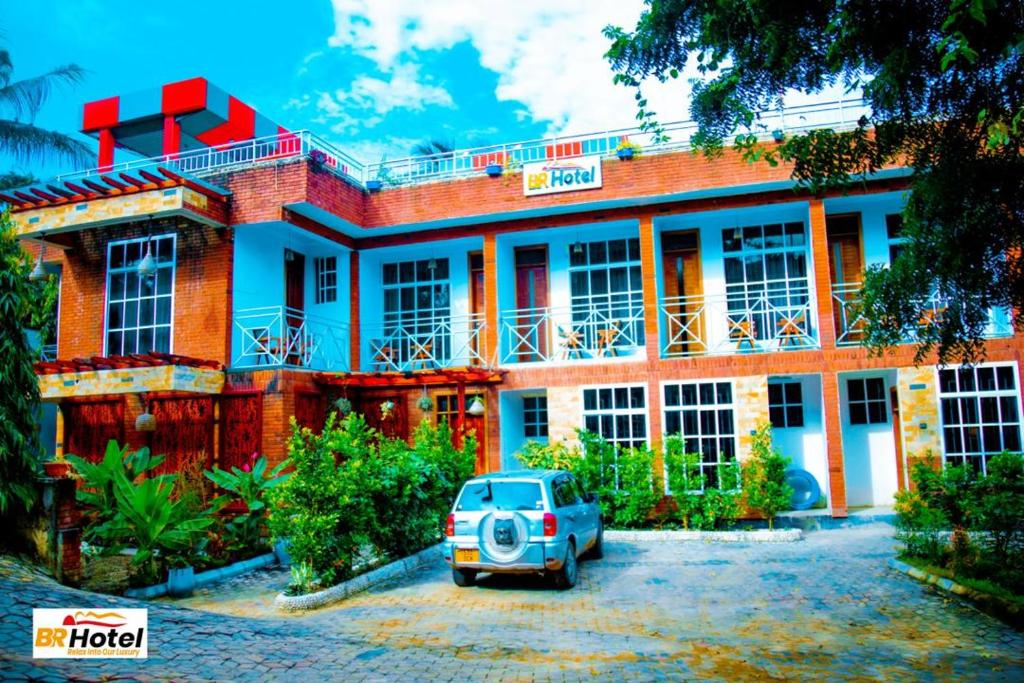 a building with a car parked in front of it at BR HOTEL & APARTMENT in Dar es Salaam