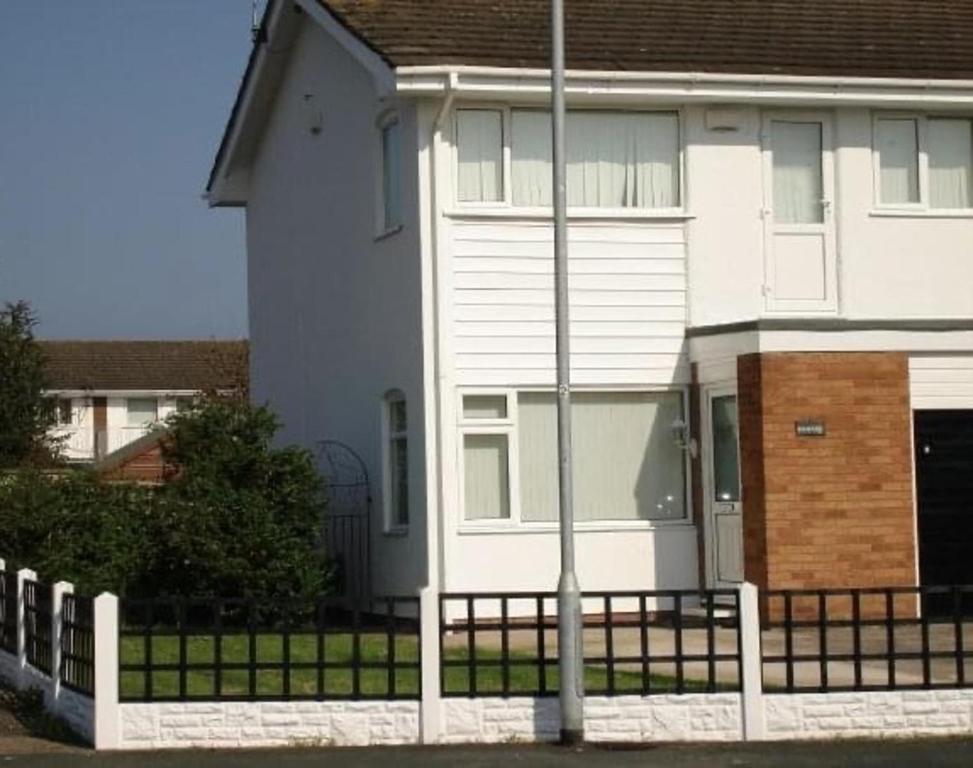 uma casa branca com uma cerca à frente. em Spacious 3 Bed House in Penrhyn Bay Llandudno em Llandudno