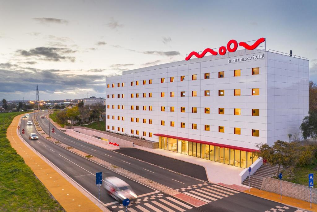 a building with a kmok sign on top of it next to a highway at Moov Hotel Oeiras in Oeiras
