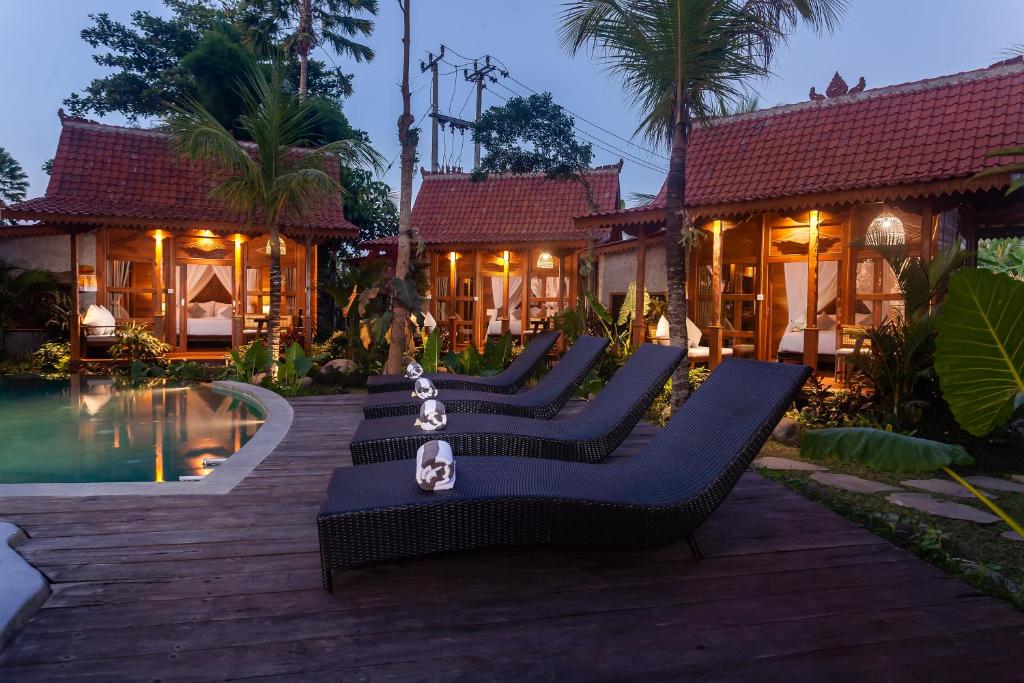 a row of chairs in front of a house at Berlima Wooden Lodge by Pramana Villas in Ubud