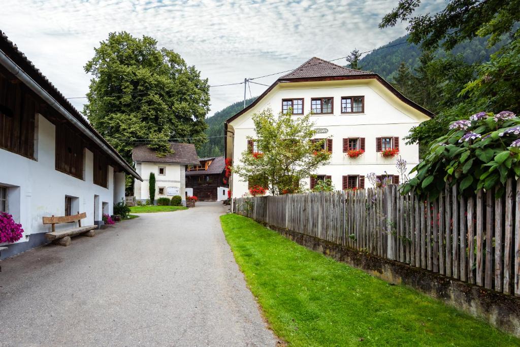 a village street with a white house and a fence at Familienbauernhof Glawischnig-Hofer in Gmünd in Kärnten