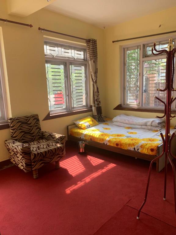 Osho Gaurishankar Meditation Center في كاتماندو: غرفة نوم بسرير وكرسي ونوافذ