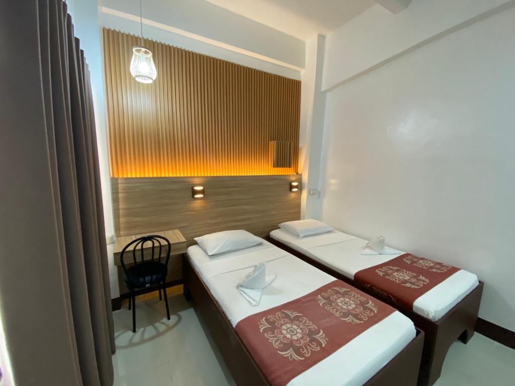 ein Zimmer mit 2 Betten und einem Stuhl darin in der Unterkunft Stone House Quezon City in Manila