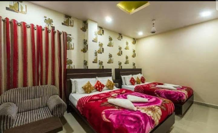 a bedroom with two beds and a chair and a couch at Hotel Royal Palace Mysuru in Mysore