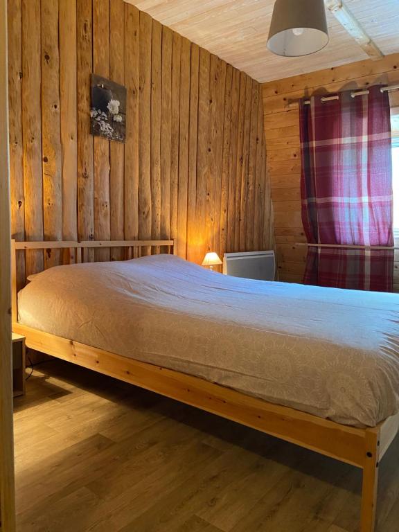 a bed in a room with a wooden wall at Le Grab in Saint-Jacques-des-Blats