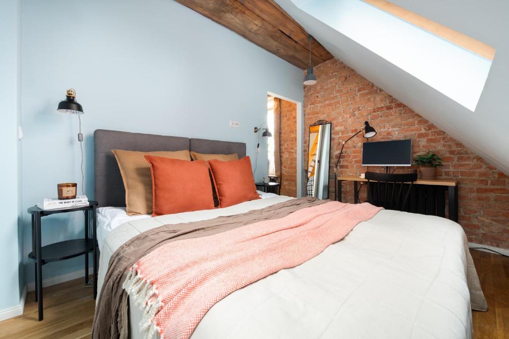a bedroom with a bed with orange pillows and a brick wall at Flatbook - In the Heart of Old Town Apartments Sw Ducha in Gdańsk