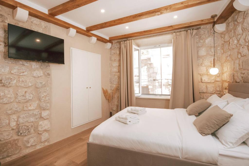 a bedroom with a bed and a tv on the wall at Mascheroni Luxury Rooms in Dubrovnik