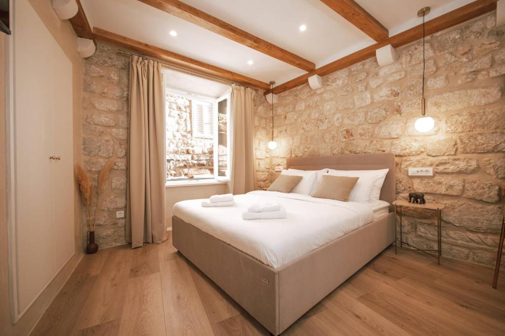 a bedroom with a large bed and a stone wall at Mascheroni Luxury Rooms in Dubrovnik