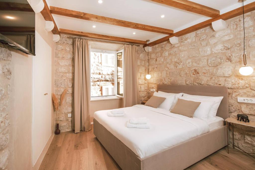 a bedroom with a large bed and a stone wall at Mascheroni Luxury Rooms in Dubrovnik