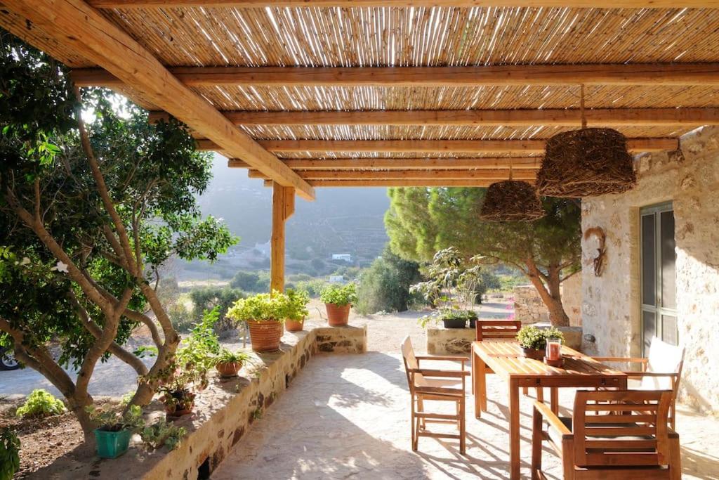 a patio with a table and chairs under a wooden pergola at Dolly's Dream House in Patmos