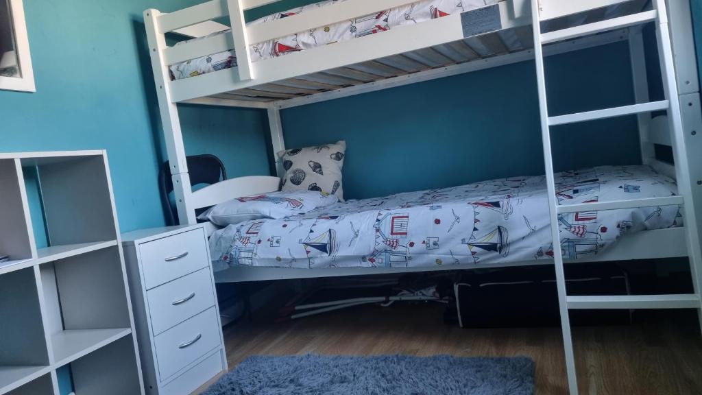 a bedroom with two bunk beds and a blue wall at 2 Bedroom 1st floor flat Brean in Brean