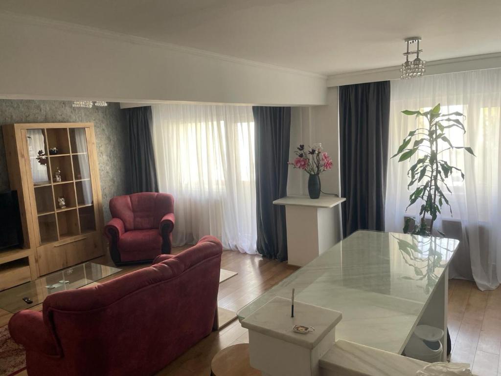 a living room with a glass table and red chairs at Mara Central in Baia Mare