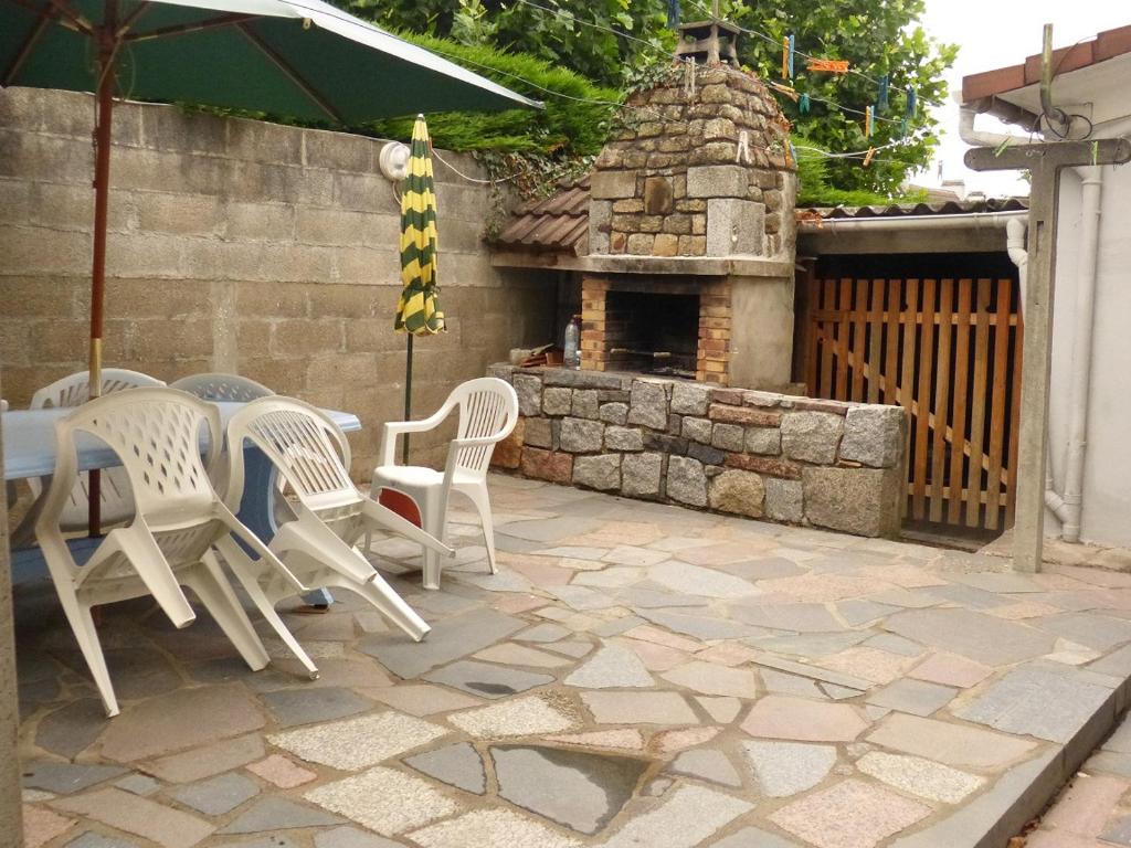 un patio con mesa, sillas y horno de piedra. en APPARTEMENT AVEC TERRASSE ET BARBECUE, en Granville