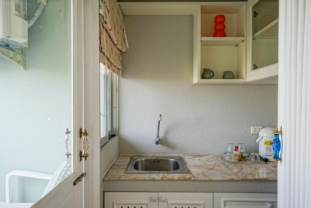 A compact kitchenette has a sink, counter, cabinets, and a window-side door opening to the balcony.