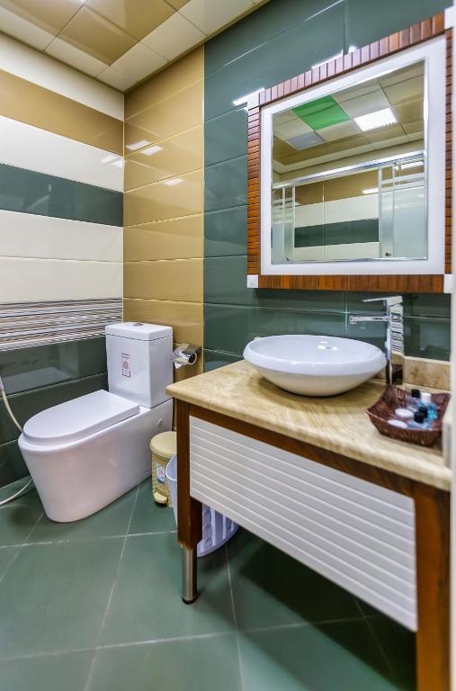 a bathroom with a sink and a toilet and a mirror at Manor Luxury Hotel Baku in Baku