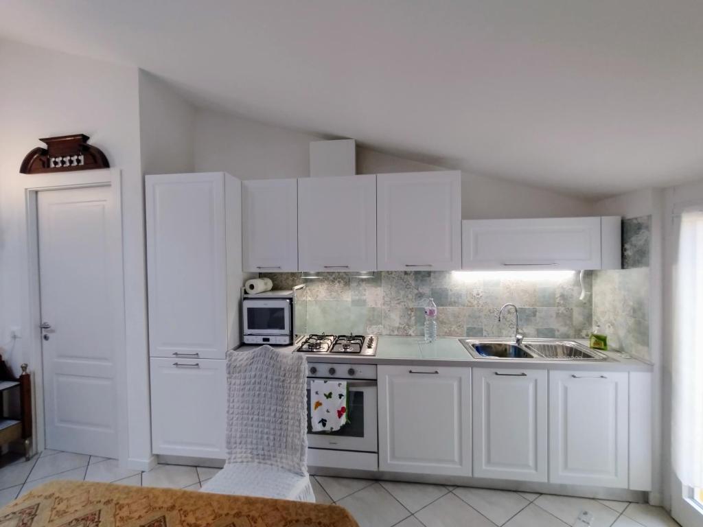 a kitchen with white cabinets and a stove and a sink at Mansarda di Masha in Villongo SantʼAlessandro