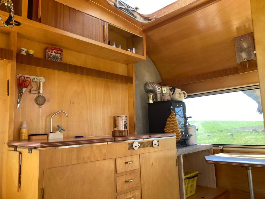 eine Küche mit Holzschränken, einem Waschbecken und einem Fenster in der Unterkunft Tiny Paradise in Bern