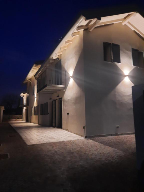 ein weißes Gebäude mit seitlicher Beleuchtung in der Unterkunft Piccola Corte in Udine