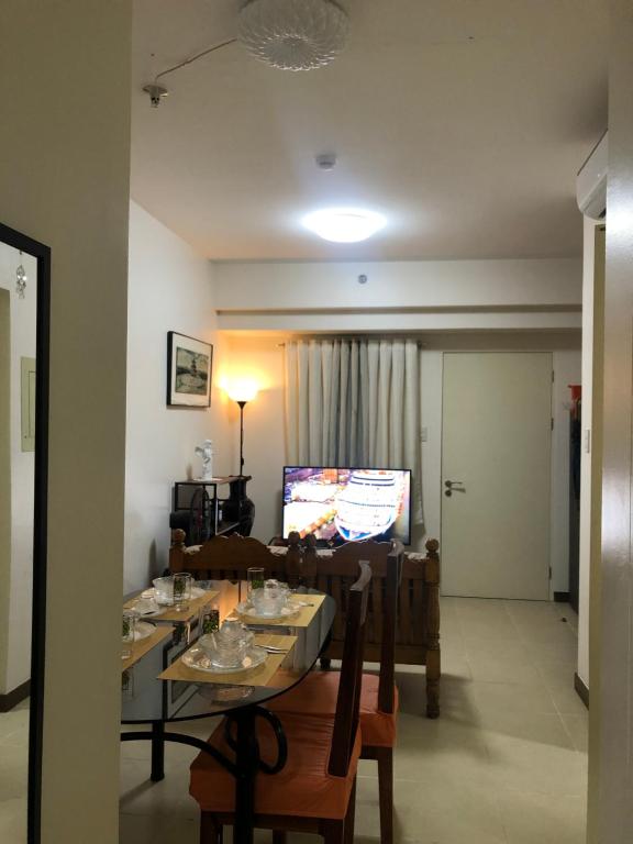een woonkamer met een tafel en stoelen en een televisie bij M&M Residence in Manilla