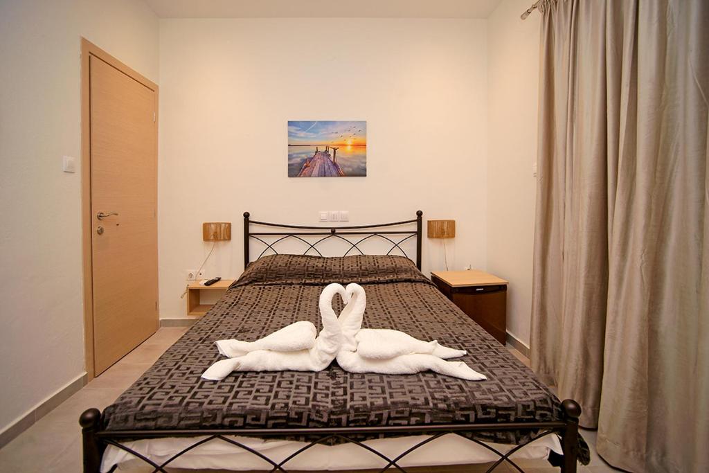 una camera da letto con 2 asciugamani cigni su un letto di Karnagio Rooms a Kyparissia
