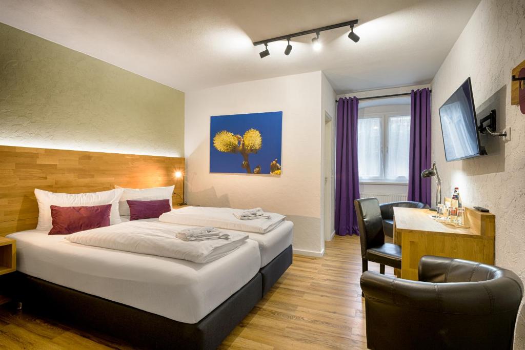 ティティゼー・ノイシュタットにあるBrauereigasthof Bärenのベッド2台とデスクが備わるホテルルームです。