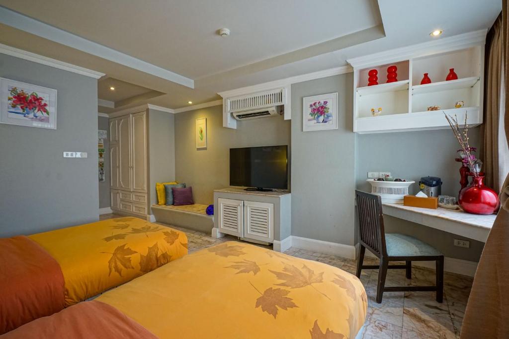 A desk with shelving sits beside the television in a bedroom furnished with twin beds.