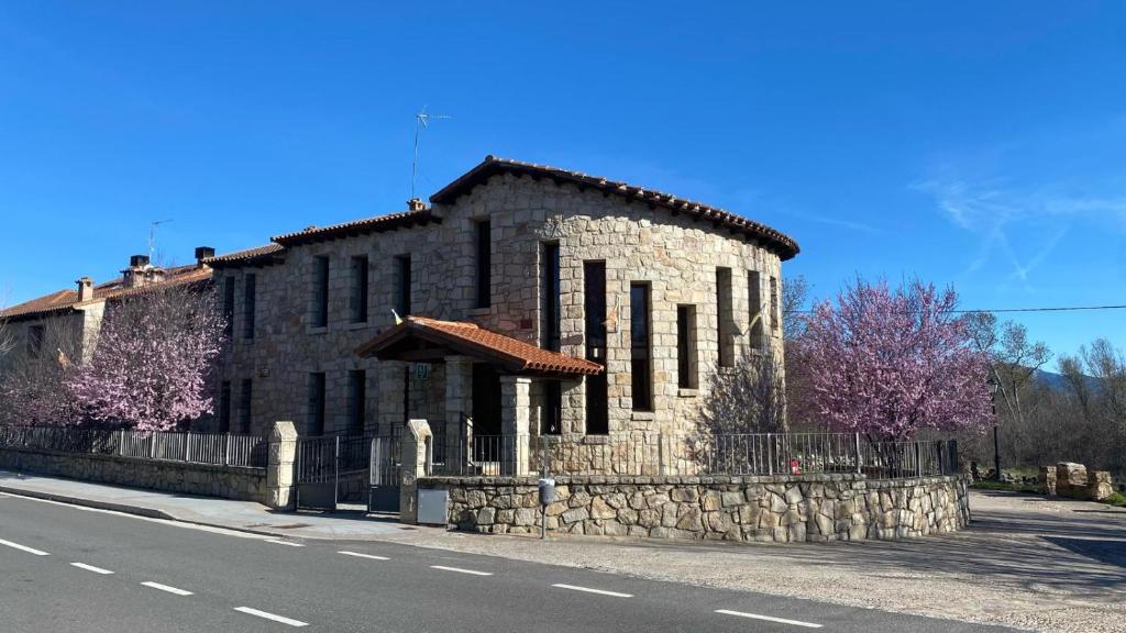 un antiguo edificio de piedra al lado de una carretera en Alojamientos La Dehesa en El Berrueco