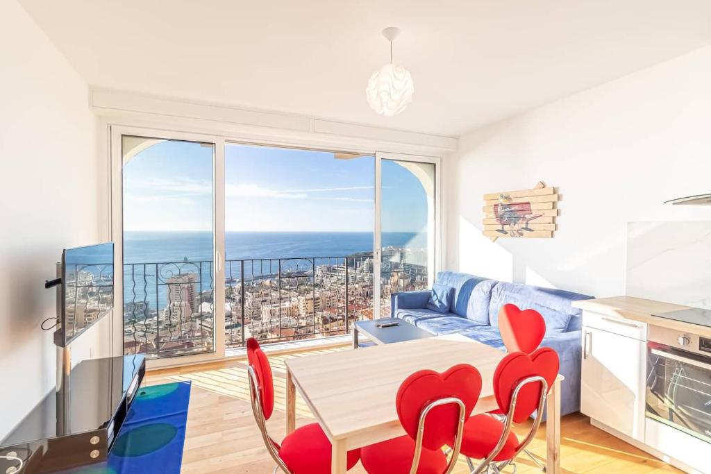 een woonkamer met een tafel en stoelen en een groot raam bij Amazing Sea View T2- Near Monaco in Beausoleil