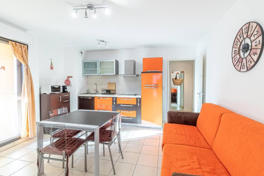 a kitchen with an orange couch and a table at Pretty T2 In Peace With Parking Menton in Menton