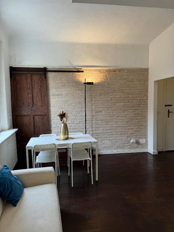 a dining room with a table and chairs and a brick wall at Maison Leone Apartment in Ravenna