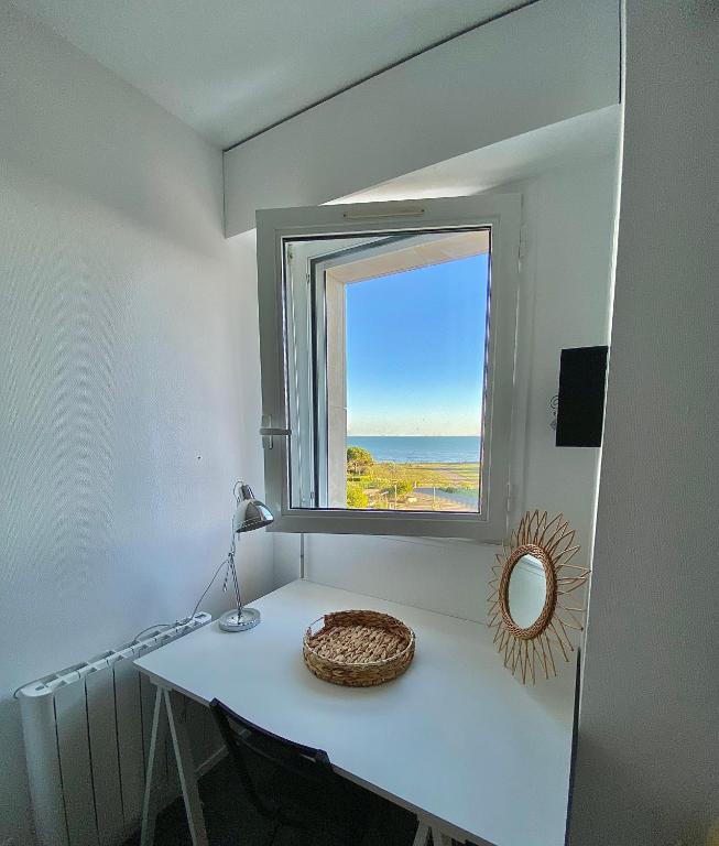 Cette chambre comprend une table avec une fenêtre et un miroir. dans l'établissement Magnifique studio La Rochelle vue mer, à La Rochelle
