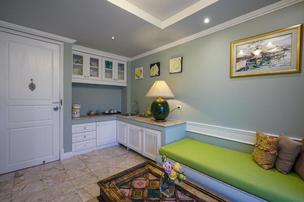 A compact sitting and kitchenette area with a green upholstered bench.