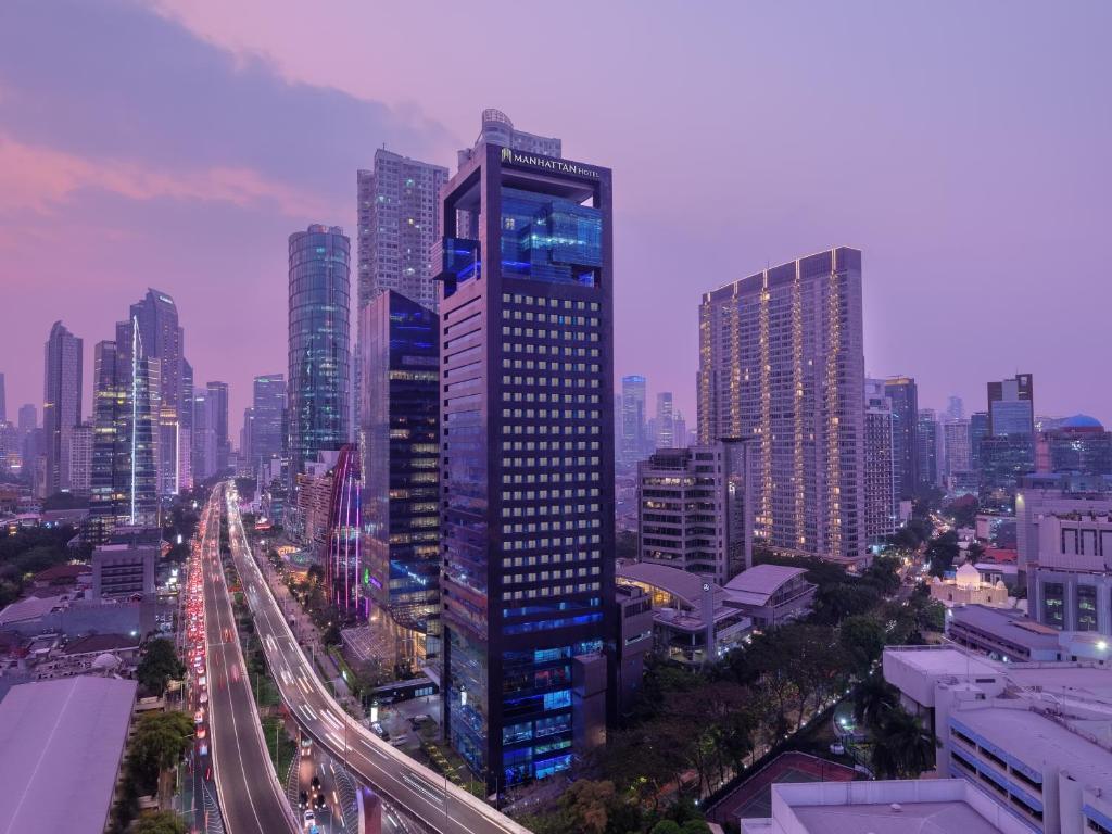 a tall building in a city with a highway at Manhattan Hotel Jakarta in Jakarta
