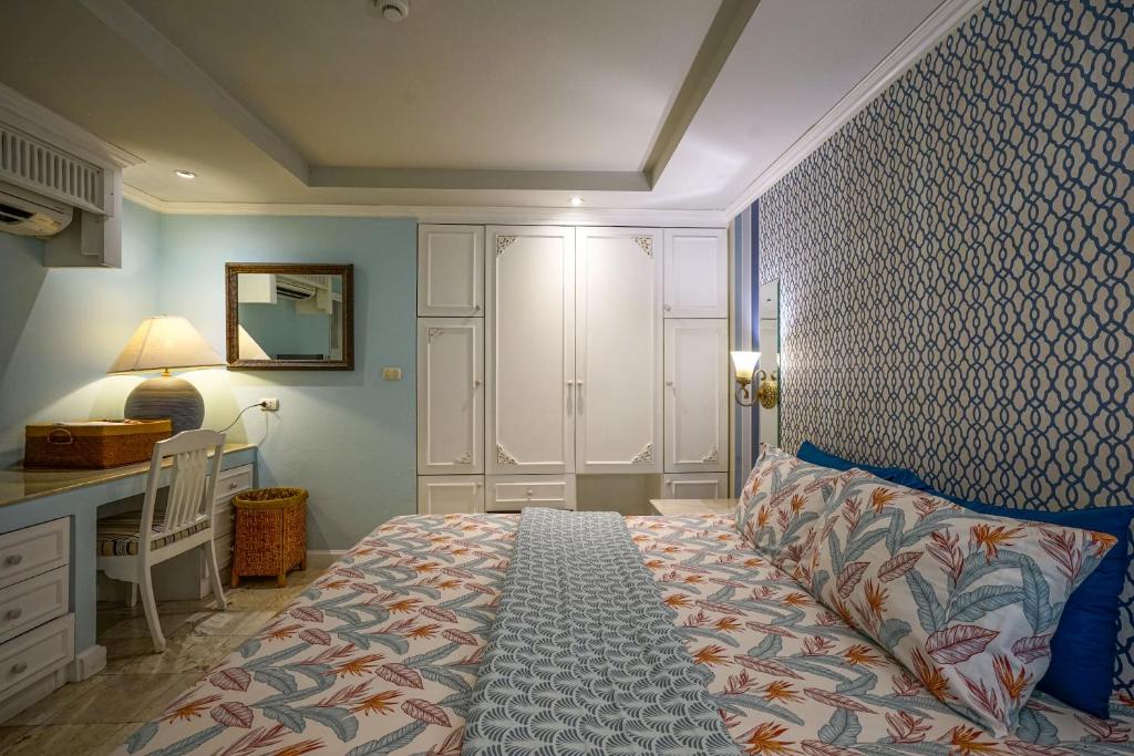 A bedroom view showing a compact desk beside the bed and extensive wardrobes.